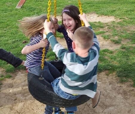 Three BGCSC members play on a tire swing at an after-school program