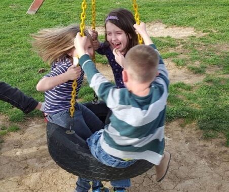 Three BGCSC members play on a tire swing at an after-school program